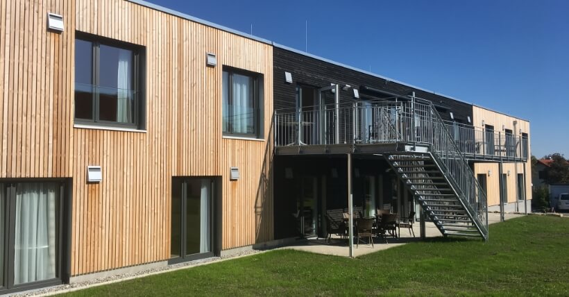 Mehrfamilienhaus mit energieeffizienter Holzfassade und einem Stahltreppenaufgangs.